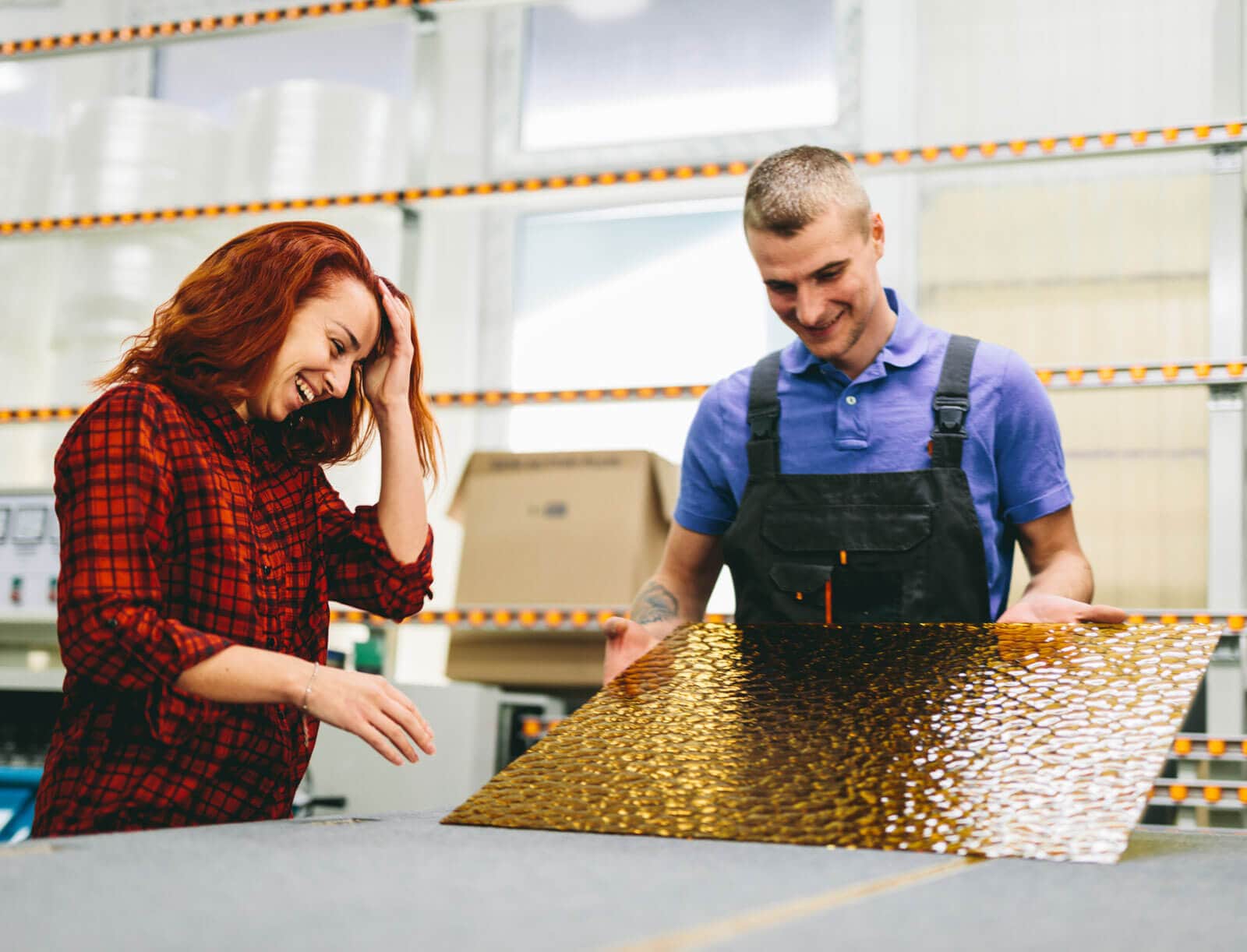 Man and woman working on glass pane in glazier